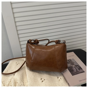 Detail of caramel brown soft leather handbag with silver zipper on a knit sweater