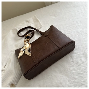 Detail of vintage brown tote bag with decorative silk scarf on a soft knit background
