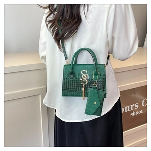 Detalle de bolso de mano verde oscuro efecto cocodrilo con hebilla S dorada y borla