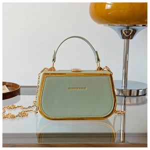 Detailed view of sage green box handbag with gold metal trim and chain strap details