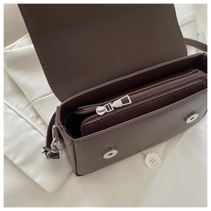 Detail view of the deep brown leather bag showing inner compartments and magnetic buckles