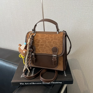 Retro brown and leopard print crossbody bag with bear charm on a stack of books