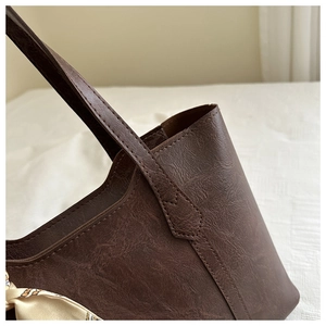 Detail of vintage brown tote bag featuring pleated leather texture and floral silk scarf