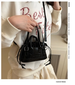 Détail du sac à main noir motif crocodile avec doublure à cordon et bandoulière