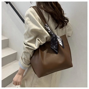 Brown leather tote bag featuring a geometric silk scarf detail on handle shown on model