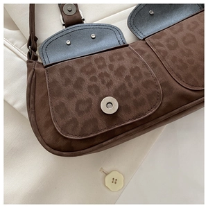 Close-up of leopard print shoulder bag with magnetic buckle on beige suit background