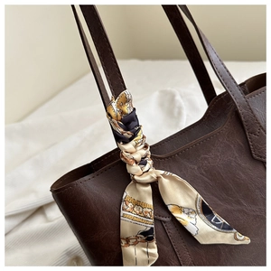 Detail of vintage dark brown leather tote bag with elegant floral silk scarf on handle