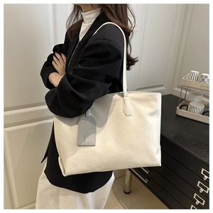 Detail of soft cream white tote bag with flexible texture and geometric pendant charm