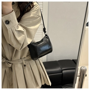 Détail du sac sous le bras en croissant noir brillant avec bandoulière à nœud et anneaux
