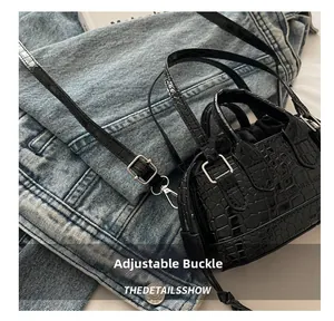 Détail de la boucle argentée et du motif crocodile sur le sac seau noir brillant