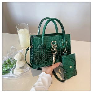 Detalle del bolso tote verde oscuro grabado en cocodrilo con logo SS y borlas de flecos