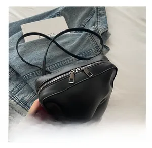Détail du sac bandoulière en PU noir avec relief visage et doubles fermetures éclair fluides