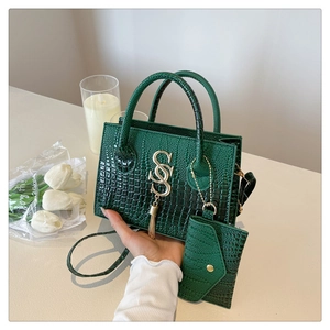Detalle de bolso verde bosque grabado en cocodrilo con logo metálico y borlas decorativas