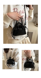 Detail of black crocodile pattern mini bucket bag with silver buckles and drawstrings