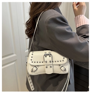 Detail view of white leather shoulder bag with silver rivets and metal buckle strap