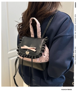 Detail of pink bow and ruffle trim on black ballet style mini backpack with heart charm