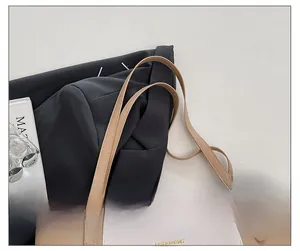 Détail d'une bandoulière en cuir réglable avec boucle dorée sur un sac cabas beige