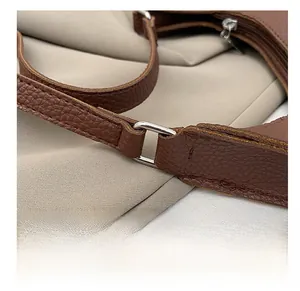 Macro view of premium silver metal D-ring and litchi texture leather on brown hobo bag