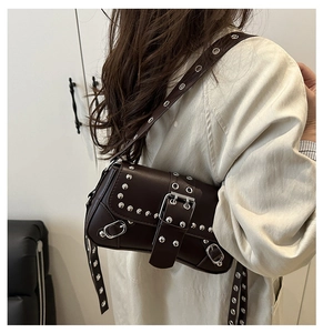 Détail du sac punk marron foncé avec rivets argentés et œillets métalliques sur la bandoulière