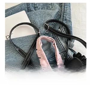 Close-up of adjustable black leather shoulder strap with white stitching and pink texture