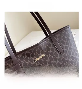 Macro view of French monogram tote bag featuring a gold brand logo and brown leather detail