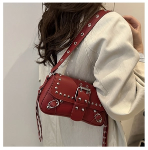 Détail du sac à bandoulière en cuir rouge avec rivets argentés et boucles biker