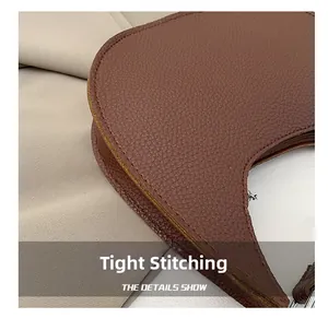 Macro shot of precise stitching and pebble grain leather texture on a brown crescent bag