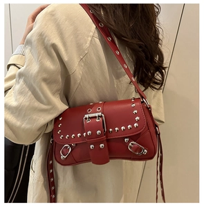Détail d'un sac bandoulière rouge vintage avec des rivets argentés et une boucle en métal