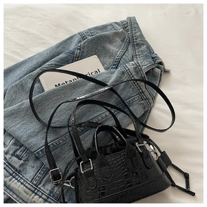 Close-up of black crocodile pattern mini tote bag with silver zipper and shoulder strap