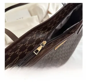 Close-up of the smooth golden metal zipper and monogram pattern on the tote bag