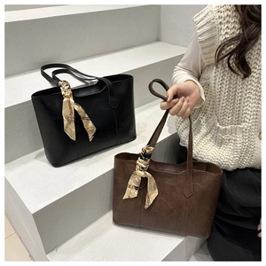 Close-up of black and brown tote bags with silk scarf detail on a white background