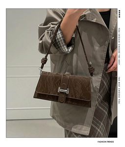 Detail of dark brown crinkled leather underarm bag with silver square buckle and knot strap