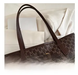 Detail of monogram pattern and gold metal logo plaque on dark brown leather tote bag