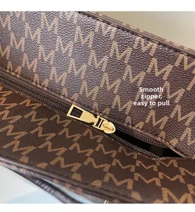 Close-up of premium golden metal zipper on vintage M-print leather tote bag