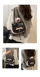Detail of sweet black PU leather mini backpack with pink satin bow and silver heart charm