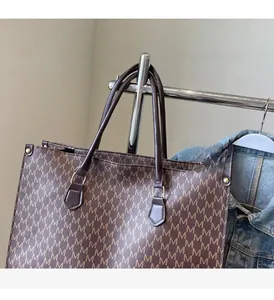 Close-up of vintage monogram tote bag with sturdy handles and golden metal buckles