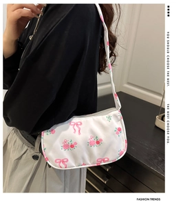 Detail of floral underarm bag with rose pattern and bow on glossy satin fabric