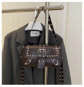 Detail of dark brown leather baguette bag with silver studs and metal buckle strap