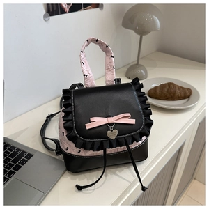 Gros plan sur le nœud rose et le pendentif cœur du sac à dos en cuir noir