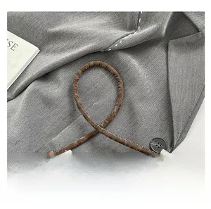 Close-up of coffee brown pleated leather bag with knotted handle and silver metal accents