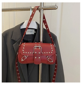Detail of red punk shoulder bag with silver rivets and metal grommets on strap