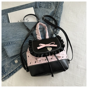 Detail of pink quilted ballet style backpack with black floral bows and heart charm