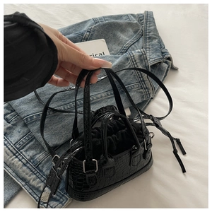 Detail of black faux leather mini bag featuring crocodile texture and drawstring inner