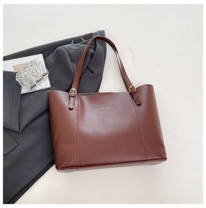 Détail d'un grand cabas en cuir marron avec texte FASHION & BAG sur un blazer gris