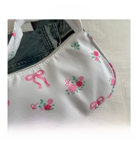 Close-up of white nylon baguette bag with pink floral rose and bow ribbon patterns