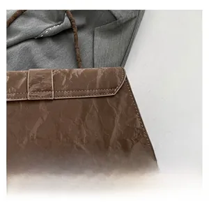 Macro detail of brown pleated leather texture and fine stitching on the shoulder bag