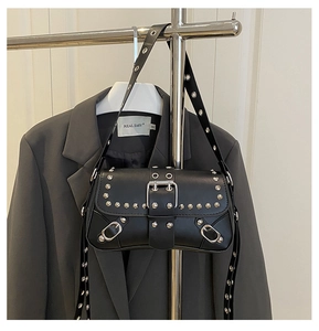 Close-up of black leather punk shoulder bag with silver studs and metal buckle strap