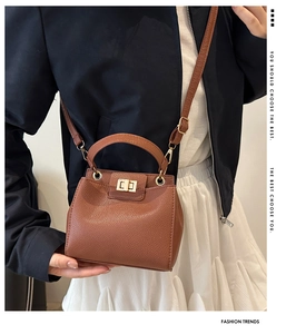 Detail of brown litchi pattern mini bag with golden metal turn-lock and handle