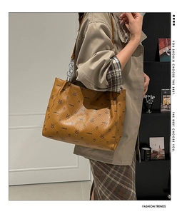 Detail of a brown tote bag featuring rabbit print and metal chain leather strap