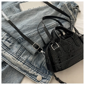 Macro detail of black crocodile pattern faux leather handbag with silver hardware